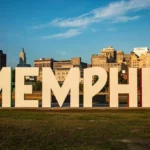 Instalación artística de grandes letras que forman la palabra MEMPHIS en un parque con el horizonte de la ciudad al fondo.