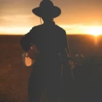 Silueta de un músico con guitarra al atardecer en el desierto