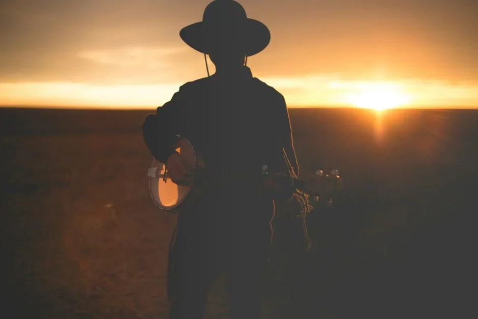 Silueta de un músico con guitarra al atardecer en el desierto