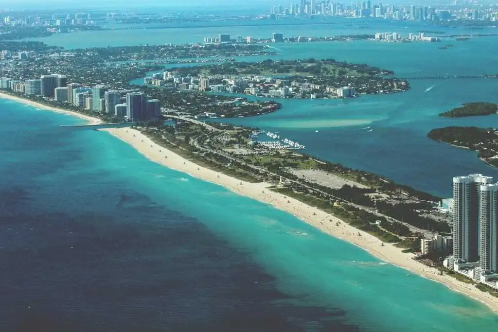 Vista aérea mostrando la impresionante costa de Miami con aguas turquesas, playas de arena blanca y edificios altos a lo largo del litoral