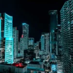 Vista nocturna de los rascacielos de Miami iluminados en tonos de azul neón, destacando la vibrante vida urbana y arquitectura moderna