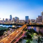 Vista panorámica del skyline de Austin, Texas, al atardecer con rascacielos iluminados reflejados sobre el río Colorado