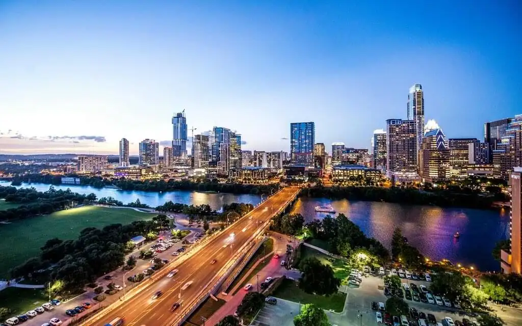 Vista panorámica del skyline de Austin, Texas, al atardecer con rascacielos iluminados reflejados sobre el río Colorado