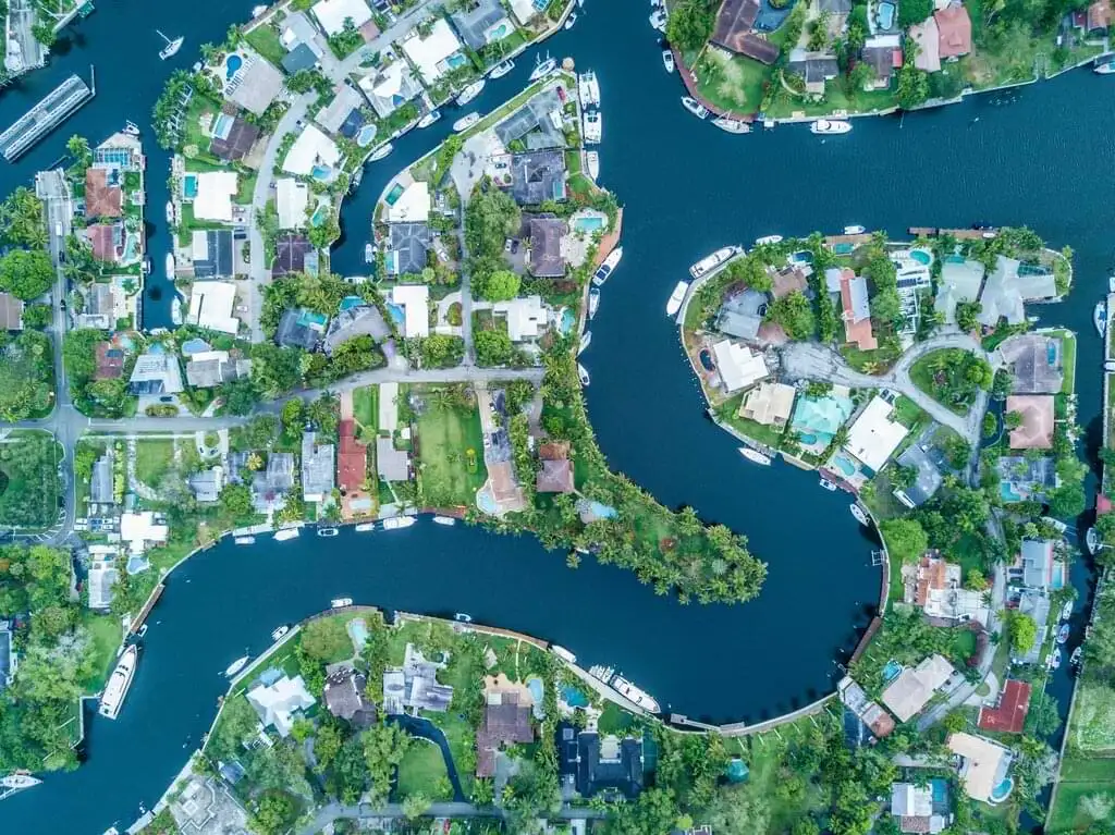 Fotografía aérea de casas lujosas a lo largo de canales serpenteantes, mostrando una comunidad residencial exclusiva con acceso directo al agua