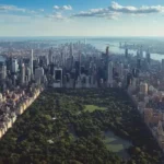 Vista aérea de Central Park en Nueva York con el impresionante skyline de Manhattan en el fondo. Se pueden apreciar los altos rascacielos rodeando el parque y el río Hudson a la izquierda. El cielo despejado con algunas nubes añade un toque sereno a la escena urbana